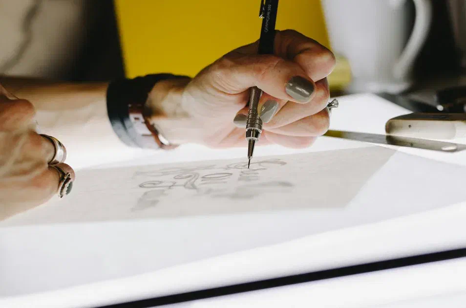 Close-up of a hand drawing a design with a mechanical pencil on paper