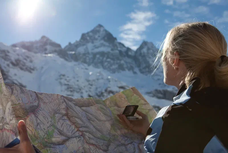 Woman holding a map and compass while navigating in snowy mountains