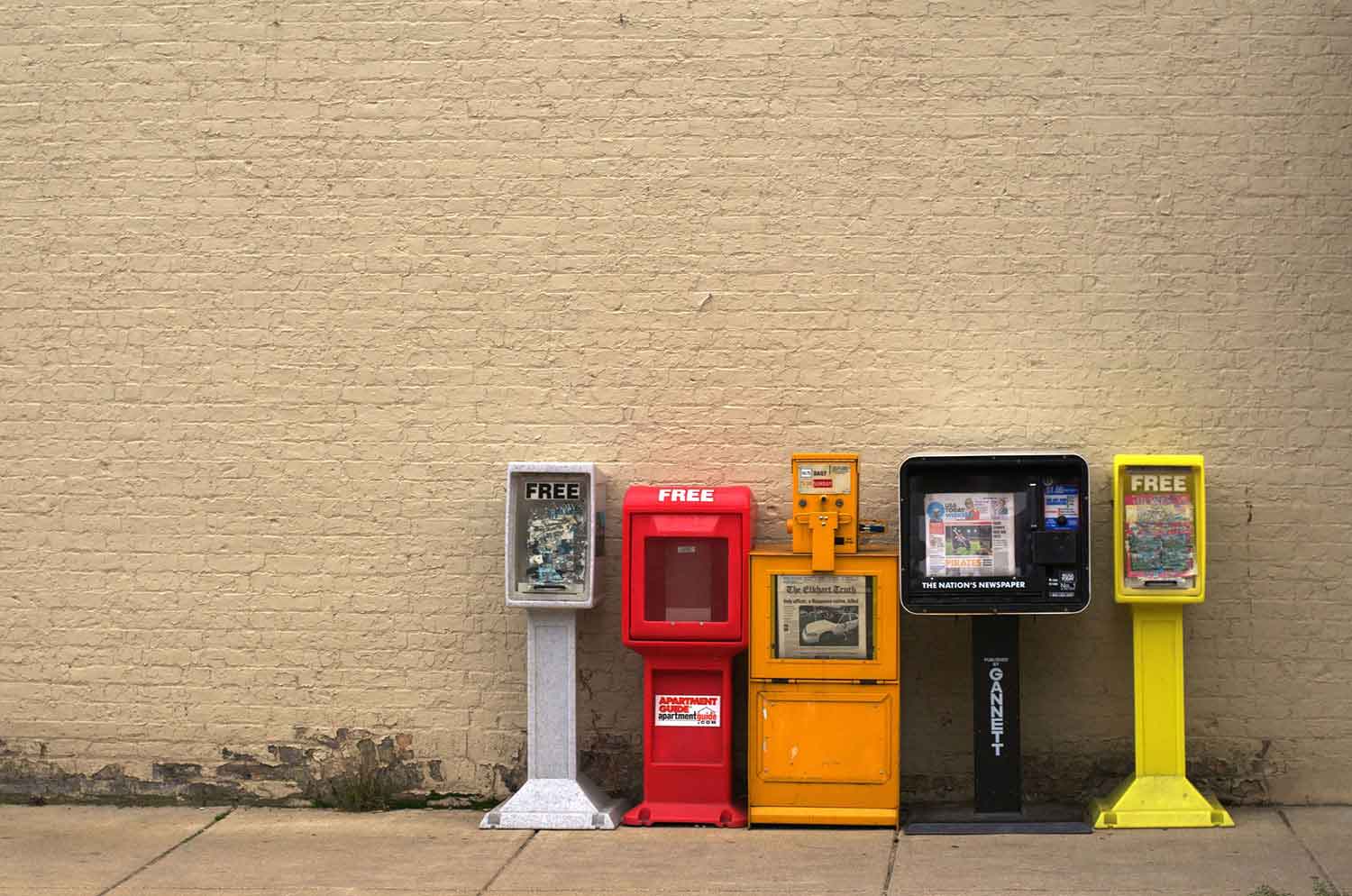 Colorful News and Magazine Boxes in fornt of a wall