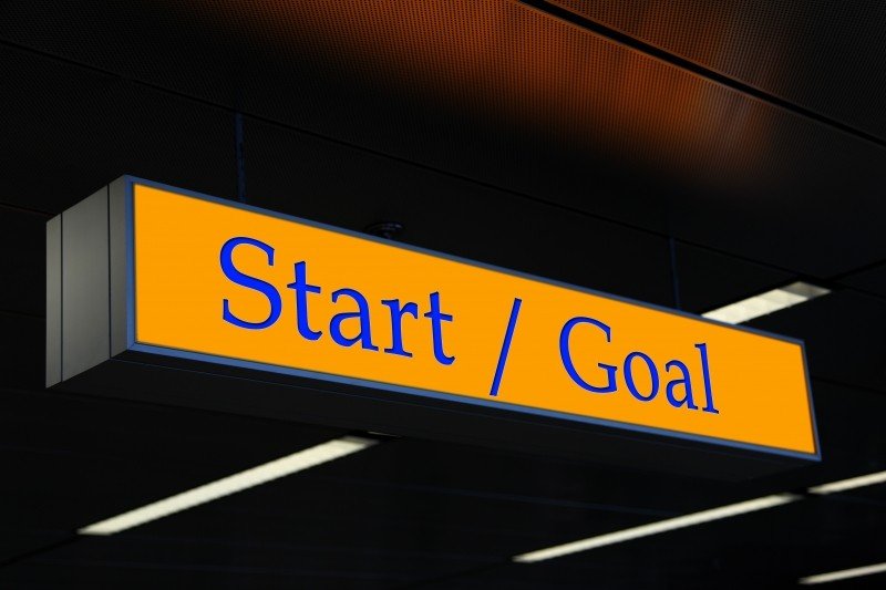 Sarı zemin üzerinde mavi harflerle Start/Goal yazan tabela