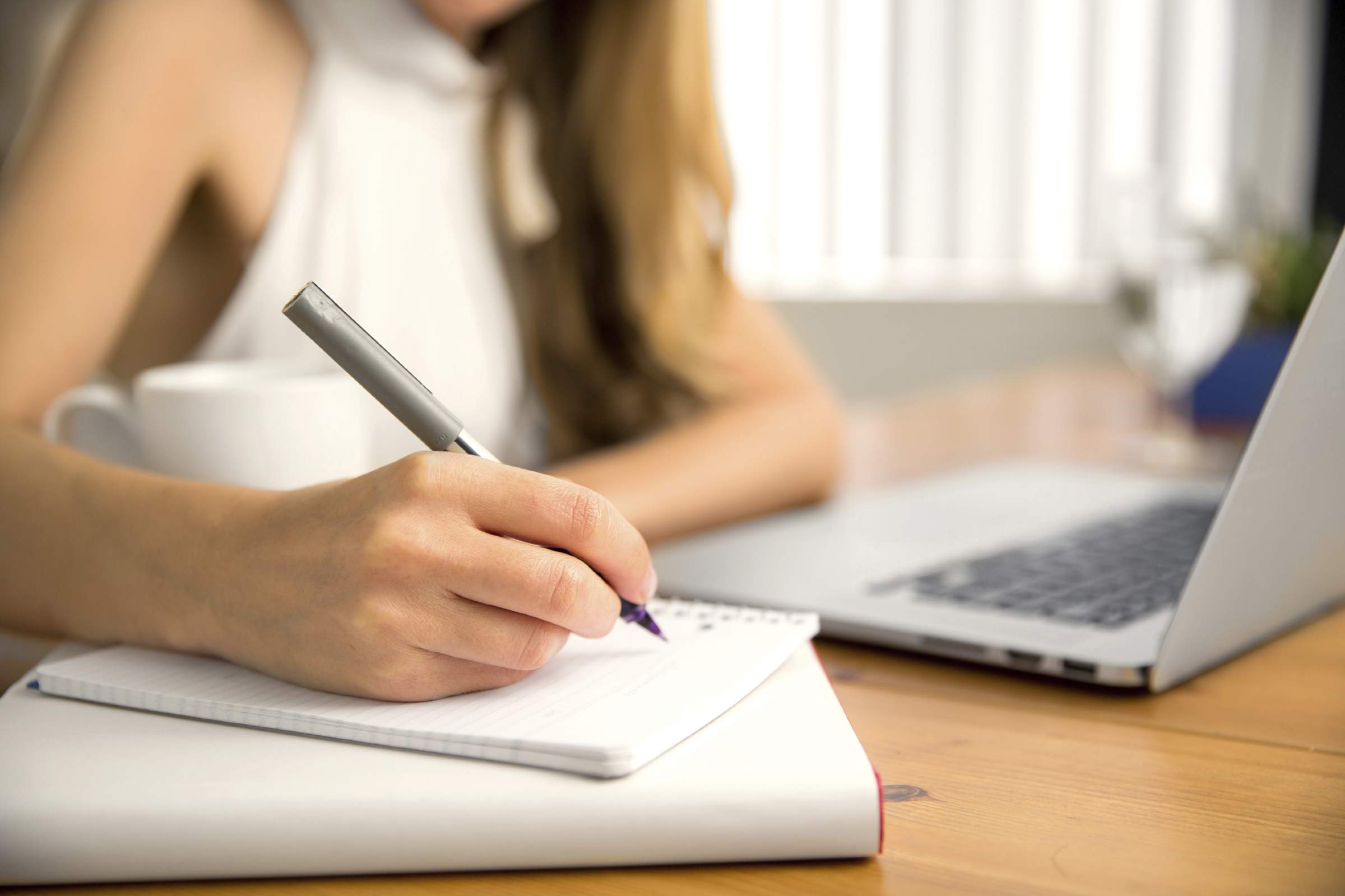 Laptop, a woman writting somthings on the notebook