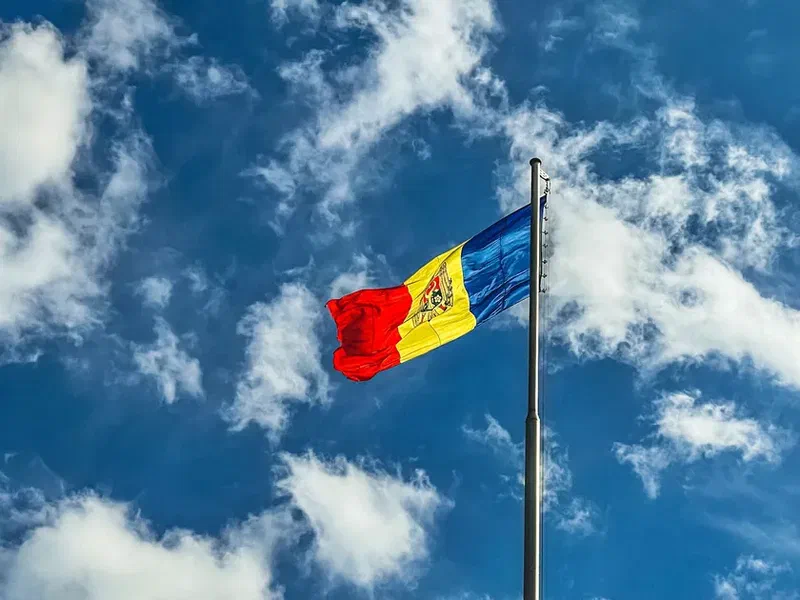 Flag of Moldova waving against a blue sky with scattered clouds