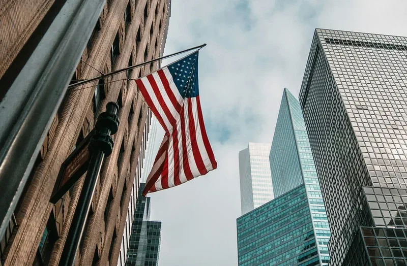 United States flag displayed among modern skyscrapers in a financial district
