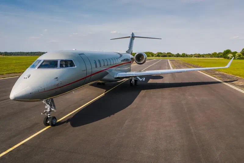 Business jet aircraft taxiing on a runway under clear sky in a flat landscape