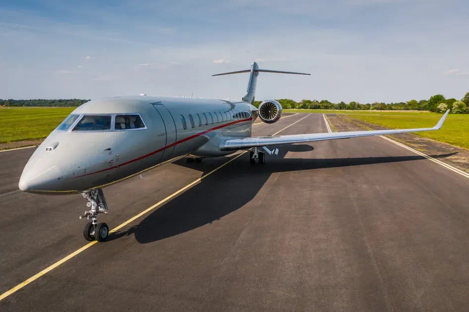 Business jet aircraft taxiing on a runway under clear sky in a flat landscape